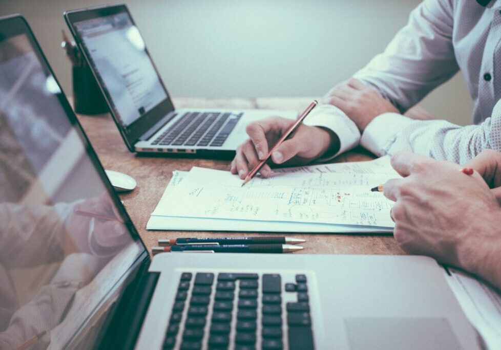 Two people working through paperwork with a laptop and notes
