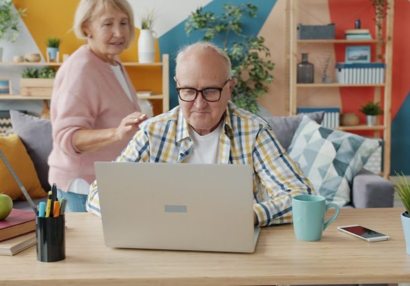 Older couple checking figures together on a laptop at home
